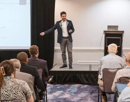 Jamie Hopkins speaking on stage at an event