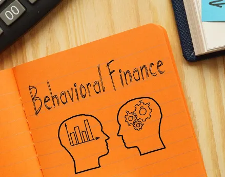 "Behavioral Finance" written on an orange notepad