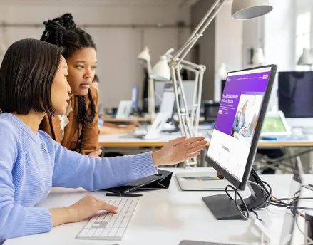 Two female coworkers looking at a computer together