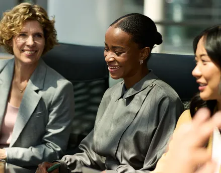 Three professional females sitting at a conference table in a meeting