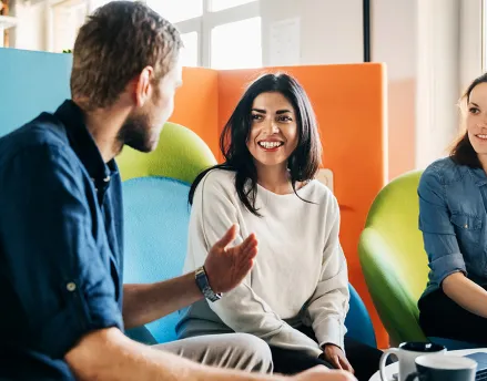 Two women and a man talking in the office